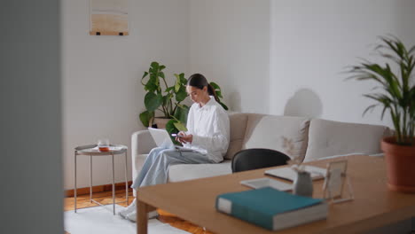 relaxed businesswoman working home sofa. lady studying laptop checking cellphone