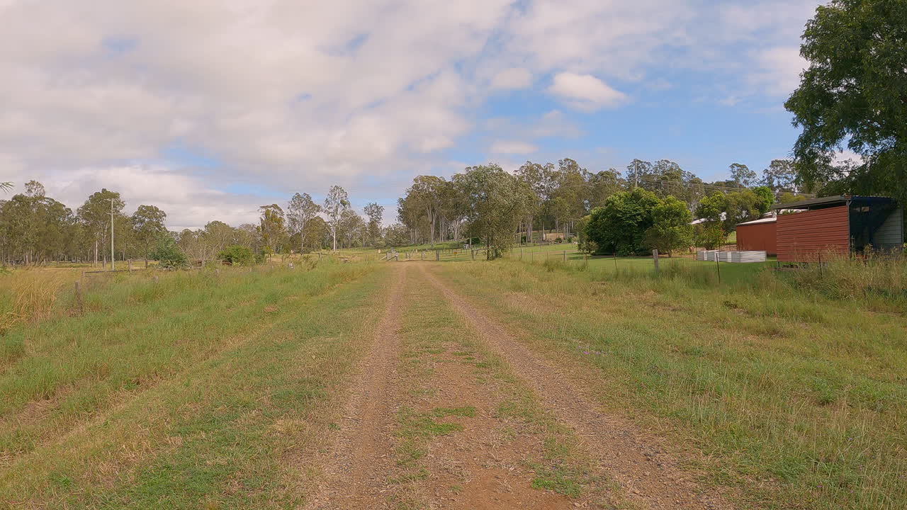punto de vista de los excursionistas que caminan por la antigua línea ferroviaria, bordes elevados, camino de grava, cobertizos viejos y árboles a lo largo, sendero ferroviario del valle de brisbane, qld 4k