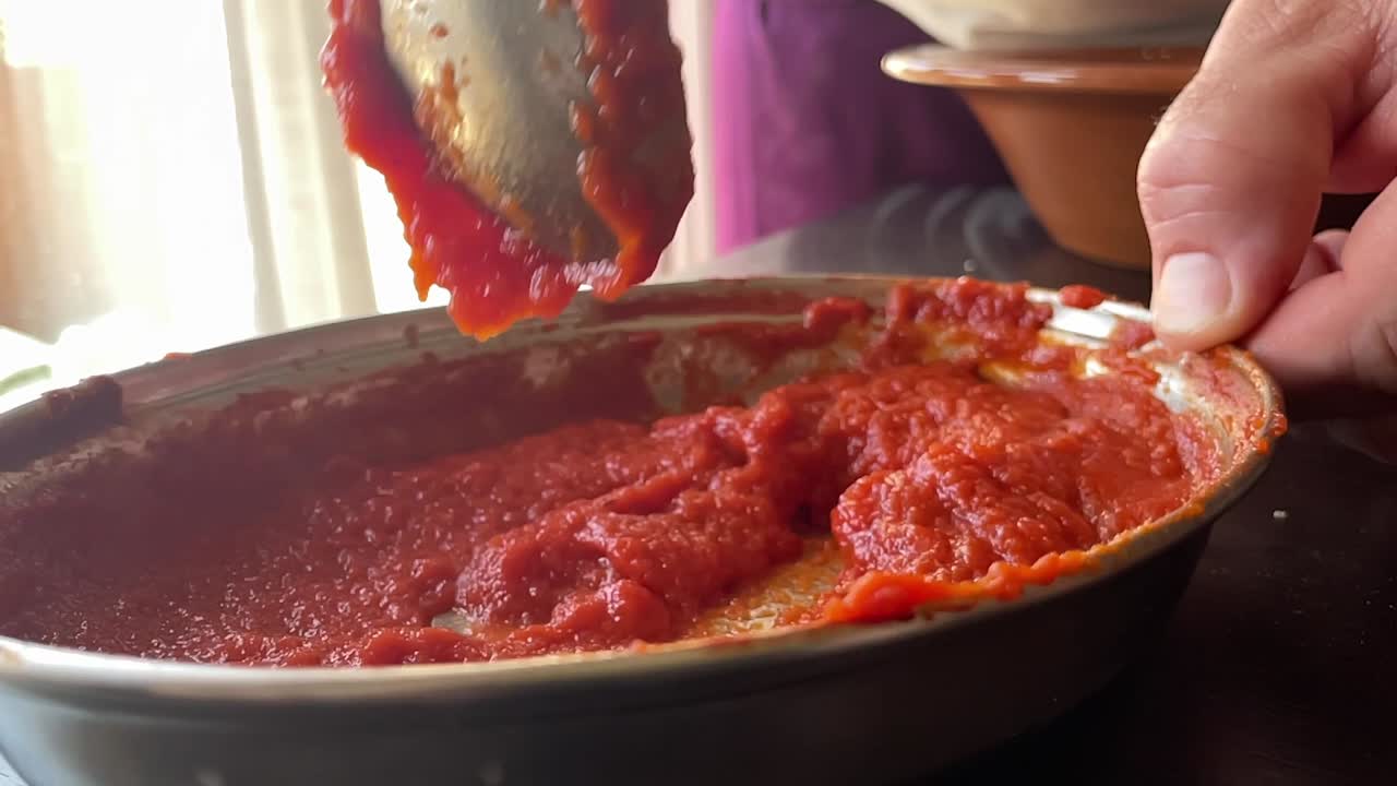 mezclar salsa de tomate para espagueti o pizza en la cocina de cerca en cámara lenta