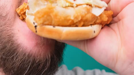 close up of a man biting a burger on a chroma key. the concept of unhealthy and unhealthy diets, high cholesterol