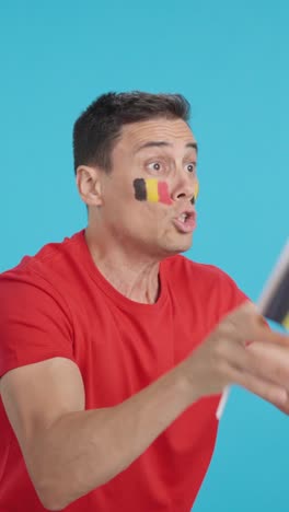 Man cheering for Belgium waving a national flag looking away