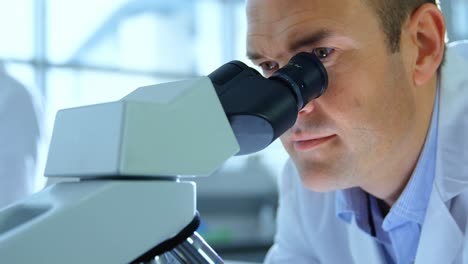 científico masculino usando el microscopio en el laboratorio 4k