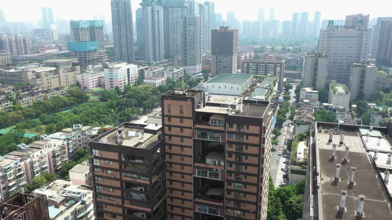 Aerial view of Chengdu cityscape blending modern high-rises with lush greenery, featuring a tall apartment building resembling a giant dollhouse under bright daylight. China, UHD.