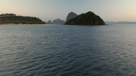 Vuelo-Aéreo-A-Baja-Altura-Sobre-El-Agua-Que-Muestra-La-Isla-Depeldet-Después-De-La-Puesta-Del-Sol,-El-Nido,-Palawan,-Filipinas