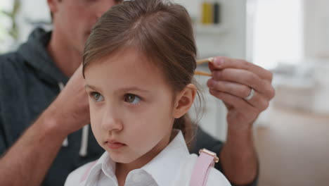 padre preparando a su hija para la escuela padre ayudando a la niña a poner un lazo en el cabello besándola de despedida 4k