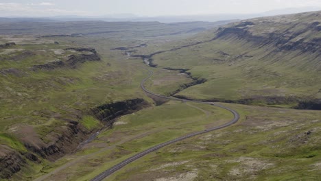 Kippbares-Drohnenvideo-In-Island-Mit-Blick-Auf-Eine-Wunderschöne-Grüne-Straße,-Die-Sich-Durch-Das-üppige-Tal-In-Der-Nähe-Von-Bifrost-Im-Norden-Islands-Schlängelt