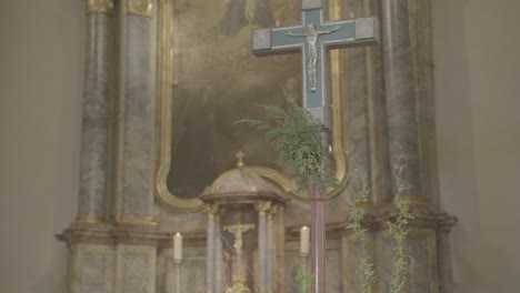 camera pans to a cross in the sanctuary of a church with a baroque altar in the background