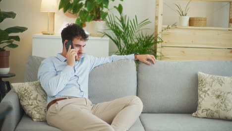 happy man talks on phone sitting on sofa