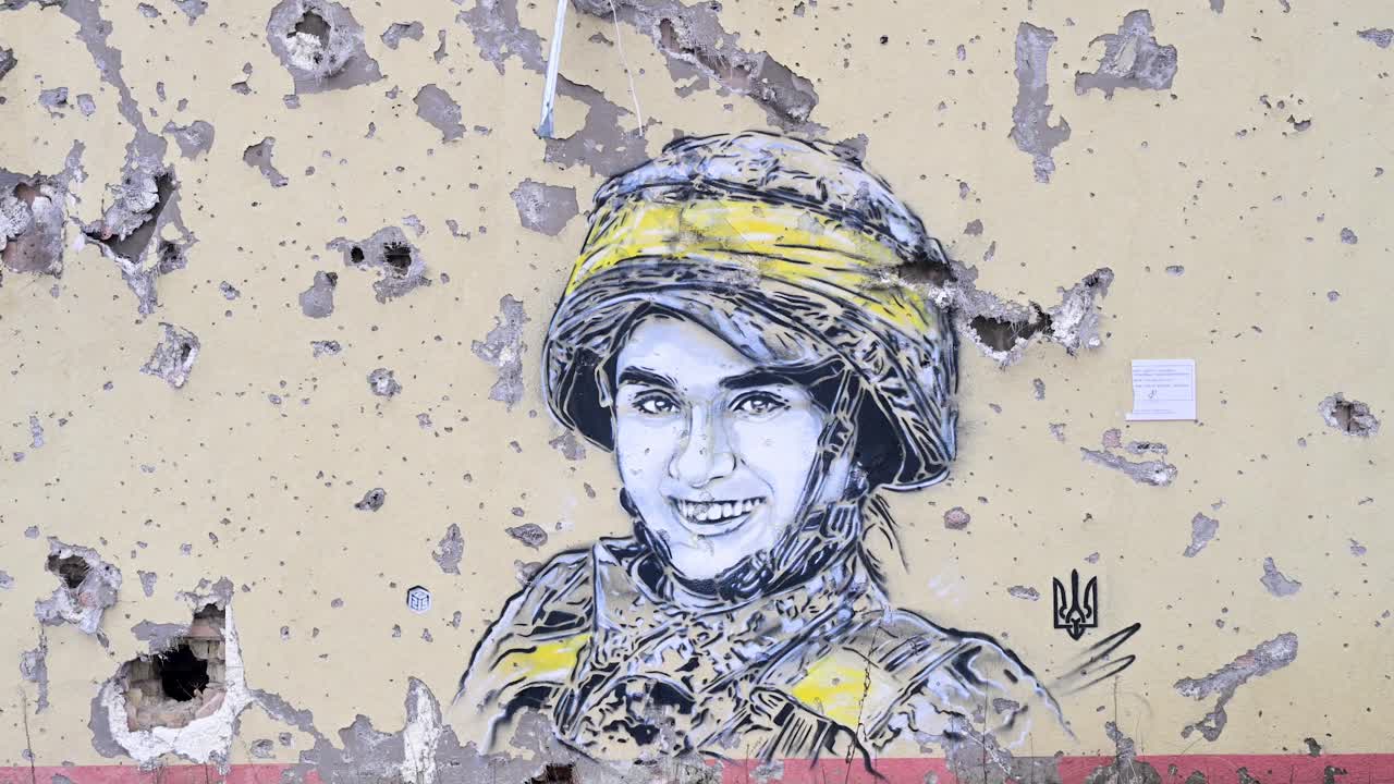 A Ukrainian soldier mural, marked by bullet and shrapnel holes, stands on a heavily damaged building in Irpin, Ukraine, amid the Ukraine-Russia conflict.