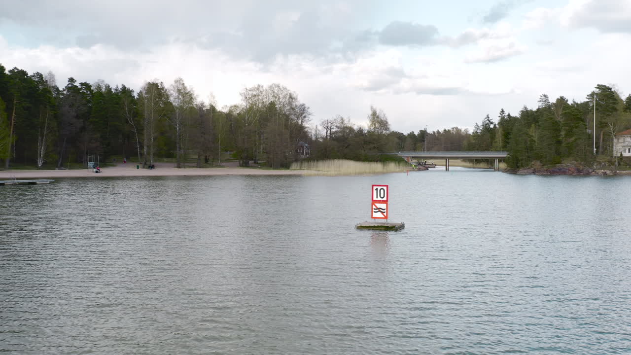 A wake and speed sign can be seen floating in a lake in Suviisaaristo a maritime district in Espoo, Finland