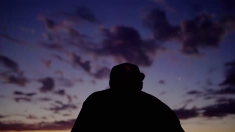 silhouetted man in baseball cap at dusk