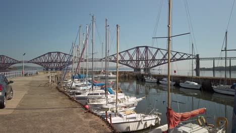 Harbor-with-the-Forth-Railway-Bridge-in-the-distance-with-calm-water-and-cloudless-sky