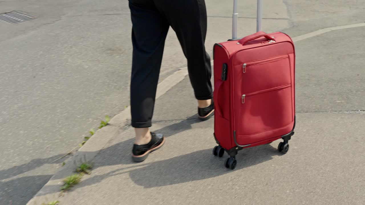 Young business woman walking with luggage in city, back view