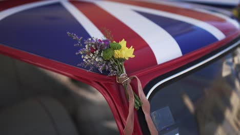 classic red car with a union jack roof, adorned with a small floral wedding bouquet
