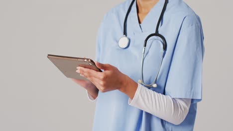 Video-Einer-Biracial-Ärztin,-Die-Ein-Tablet-Auf-Blauem-Hintergrund-Verwendet