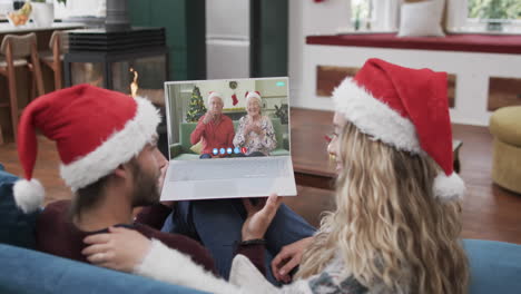 Feliz-Pareja-Caucásica-Y-Padres-Mayores-Teniendo-Videollamada-Navideña-Con-Computadora-Portátil,-Cámara-Lenta