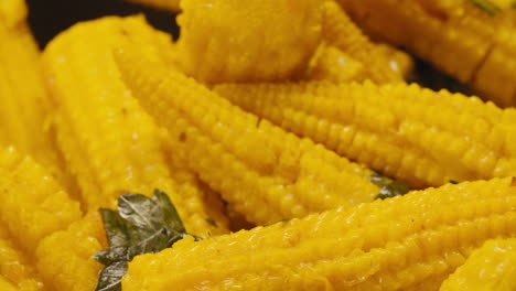 close-up of fermented yellow mini corn with black pepper on plate. preservation of vegetables in glass jars. fermentation preserved mini corns with spices macro.