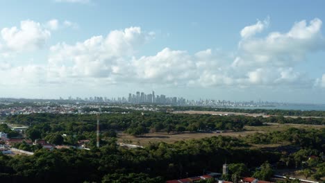 Toma-Aérea-De-Camiones-A-La-Derecha-Del-Horizonte-De-La-Ciudad-De-La-Capital-De-La-Playa-Tropical-Joao-Pessoa-En-Paraiba,-Brasil-Desde-La-Costa-De-La-Playa-De-Seixas-En-Un-Cálido-Día-Soleado-De-Verano