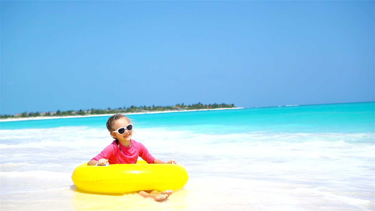una niña adorable con un círculo de goma inflable salpicando. niño divirtiéndose en las vacaciones activas de verano