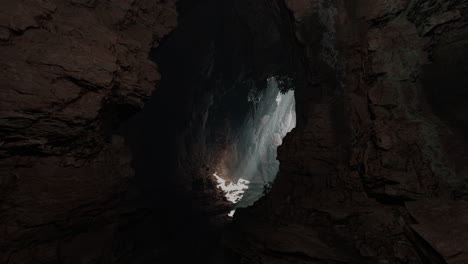 a narrow opening in a dark cave, revealing a glimpse of the world beyond