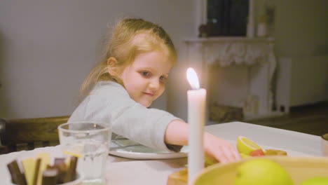 Kleines-Mädchen,-Das-Ein-Stück-Kiwi-Aufhebt-Und-Es-Während-Eines-Familienessens-Isst