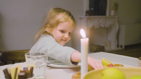 little girl picking up a piece of kiwi and eating it during a family dinner