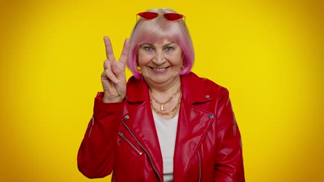 abuela madura mostrando el signo de la victoria, esperando el éxito y la victoria, haciendo un gesto de paz, sonriendo