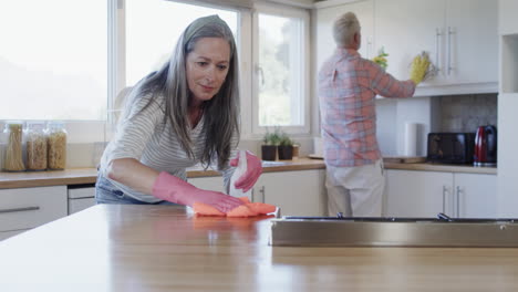 middle aged caucasian couple cleaning kitchen at home, slow motion