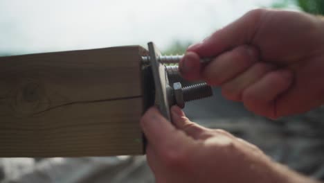 hands fastening steel plate to lumber wood with screws