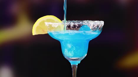 a sequence of pouring blue cocktail into a glass with a lemon slice garnish, set against a dark background.
