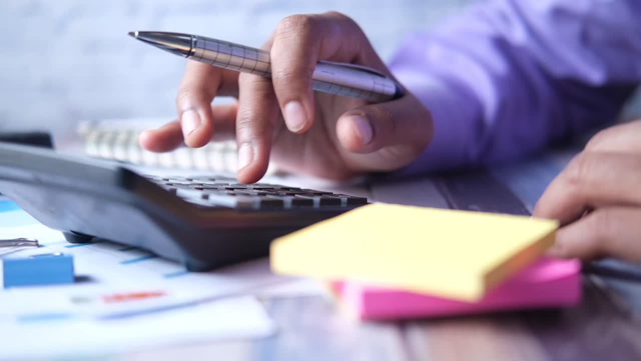 persona que utiliza una calculadora y un bolígrafo en el escritorio