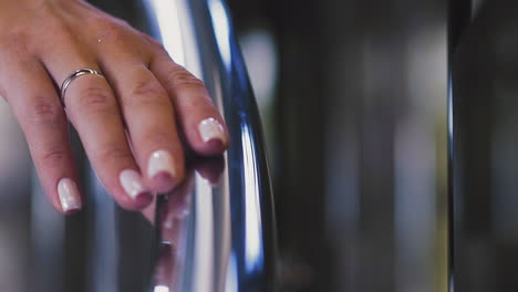 mano de mujer con manicura elegante y anillo de bodas en la barandilla