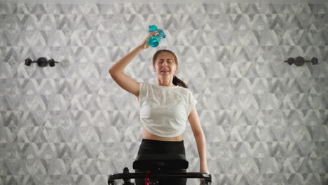 mujer cansada dispensa agua sobre la cabeza. mujer feliz corre en busca de alivio del calor generado durante el entrenamiento en la cinta de correr. sobrecalentamiento durante el entrenamiento