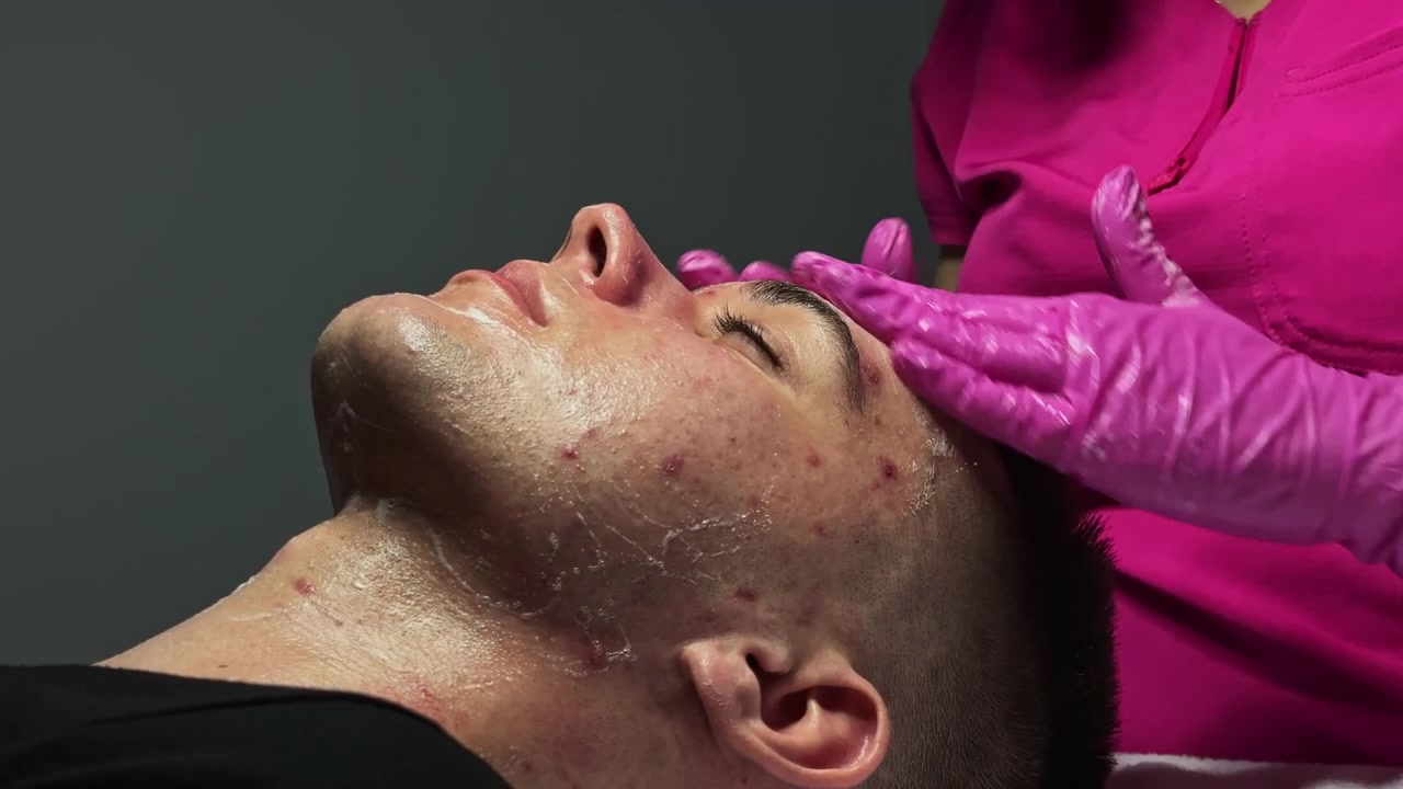 Trattamento viso in una spa con un cliente sdraiato mentre un tecnico applica prodotti per la cura della pelle durante una sessione pomeridiana