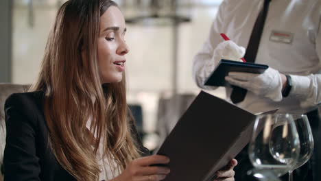 Adult-woman-ordering-food-from-restaurant-menu.-Waiter-taking-order-in-cafe