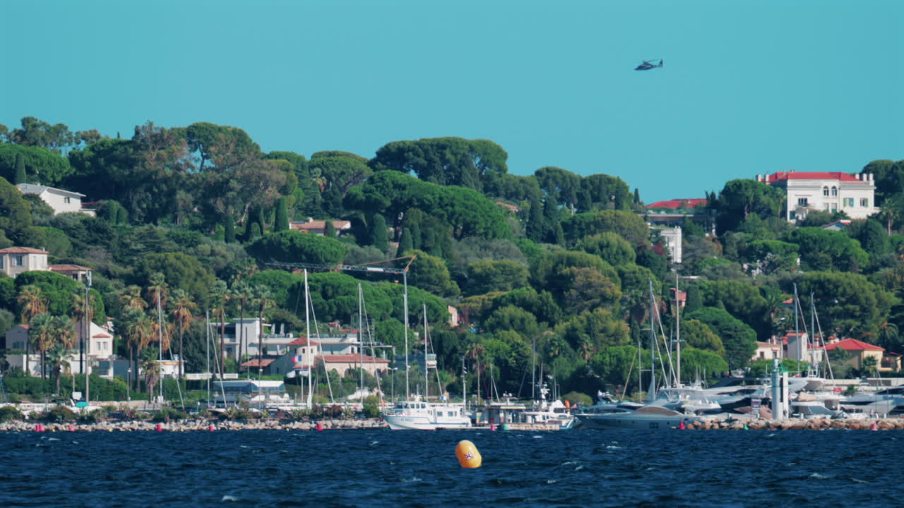 Scenic view of yachts anchored near the lush green coastline and villas of Cannes, France