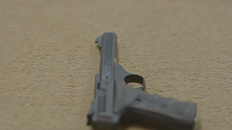 close up of man grabbing loaded firearm from carpet