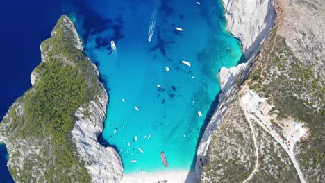 popular navagio beach - boats on turquoise blue water of coast of zakynthos in greece