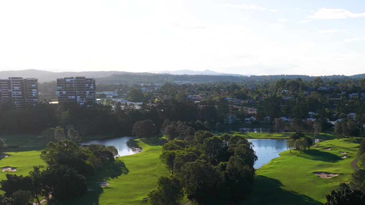 Drone footage captures a serene golf course landscape with lush greenery and water features under bright daylight