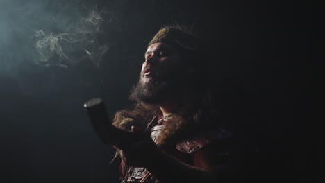 ecstatic shaman in altai costume and swirling smoke on black