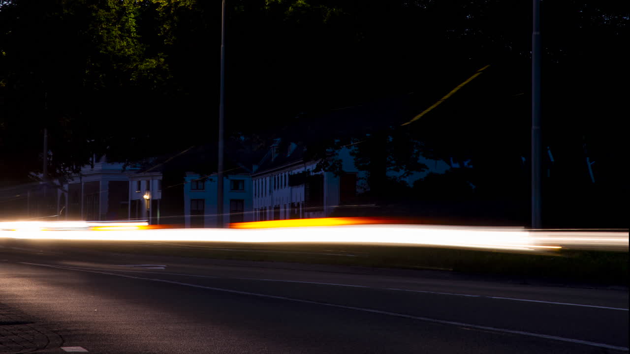 Time lapse of fast driving traffic with headlights on at sunset - pan right to left