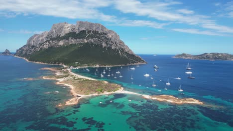 Isla-Tavolara-Rodeada-De-Barcos-Y-Mar-Azul-Durante-El-Verano-En-Cerdeña,-Italia---Antena-4k