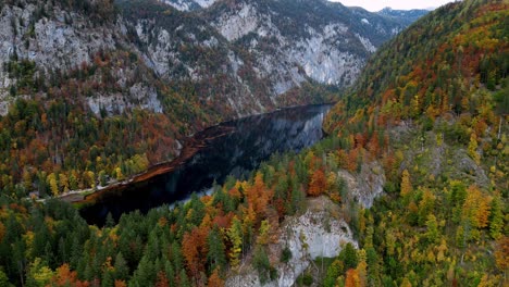 La-Imagen-Muestra-Un-Lago-Turquesa-Ubicado-En-Medio-De-Montañas-Cubiertas-De-Nieve,-Con-Exuberantes-Bosques-De-Pinos-Verdes-Que-Cubren-Las-Laderas-Inferiores,-Capturado-Desde-Una-Perspectiva-Aérea-En-Un-Día-Claro-Y-Soleado.