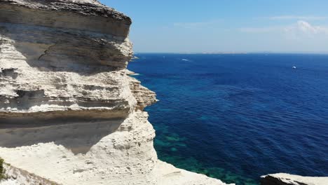 drone moving around a cliff on the foreshore slowly revealing the saint antoine beach in corsica