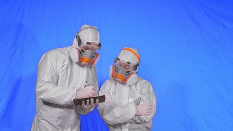 scientist virologist in respirator makes write in an tablet computer with stylus. man and woman wearing protective medical mask. chroma key blue