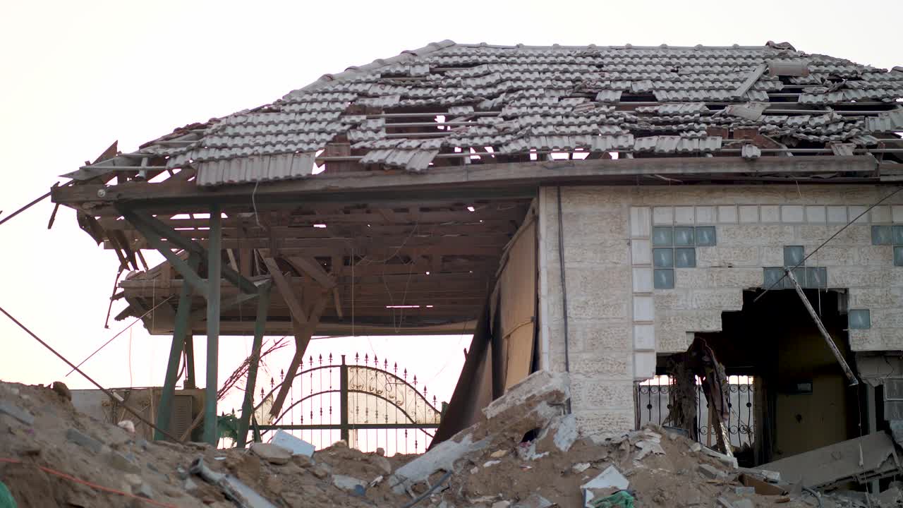 Heavily damaged house entrance in Gaza with debris and a gaping hole caused by an Israeli airstrike