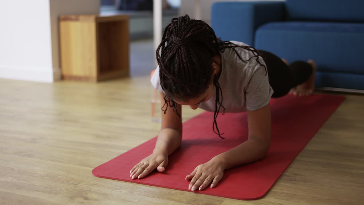 joven deportista afroamericana haciendo ejercicio de tabla en casa