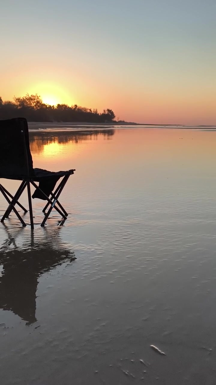 Sedia Pieghevole Vuota su Spiaggia Bagnata al Tramonto