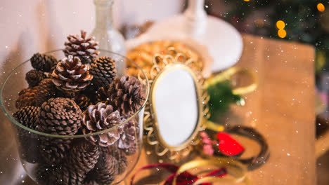 Snow-falling-over-multiple-pine-cones-in-a-glass-bowl-on-wooden-table