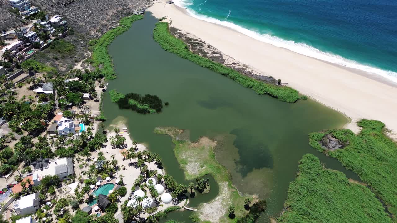 Aerial shot of a hotel in front of a lagoon and the ocean.